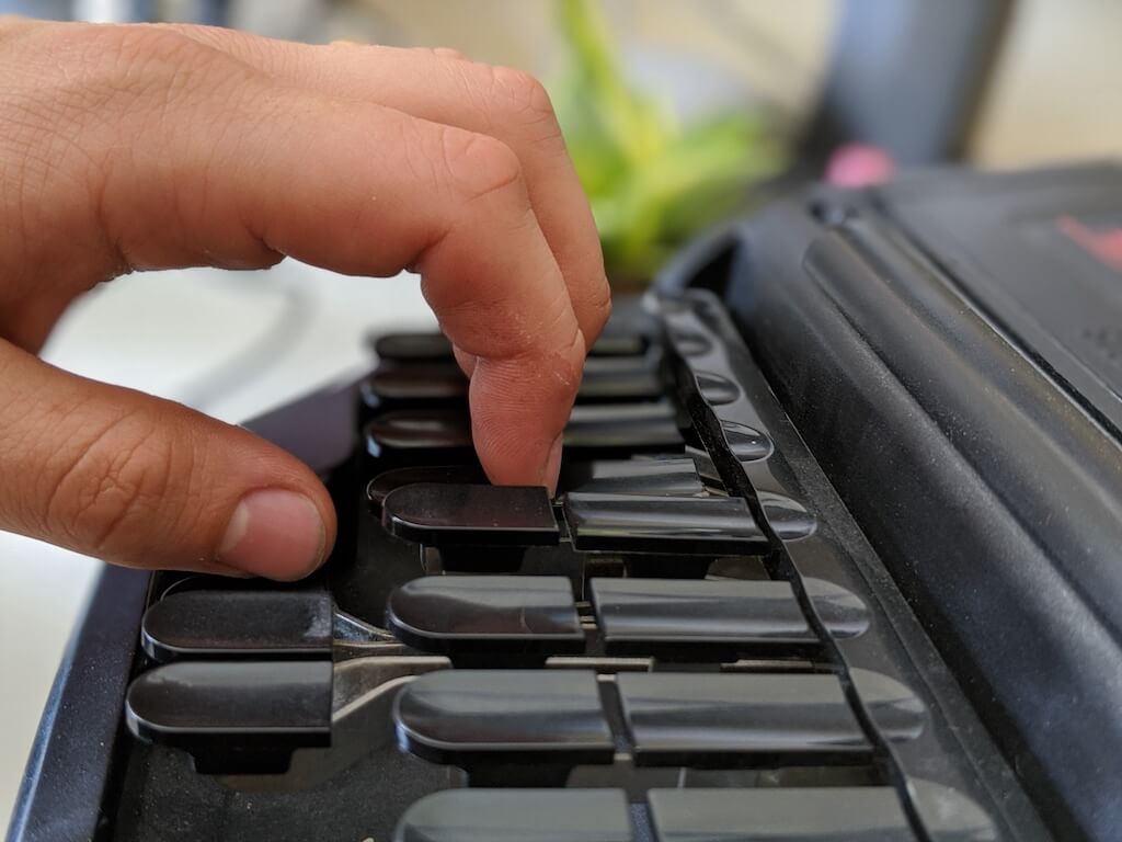 Stenographer hitting both the top and bottom key of a column by pressing down on the crack between the keys